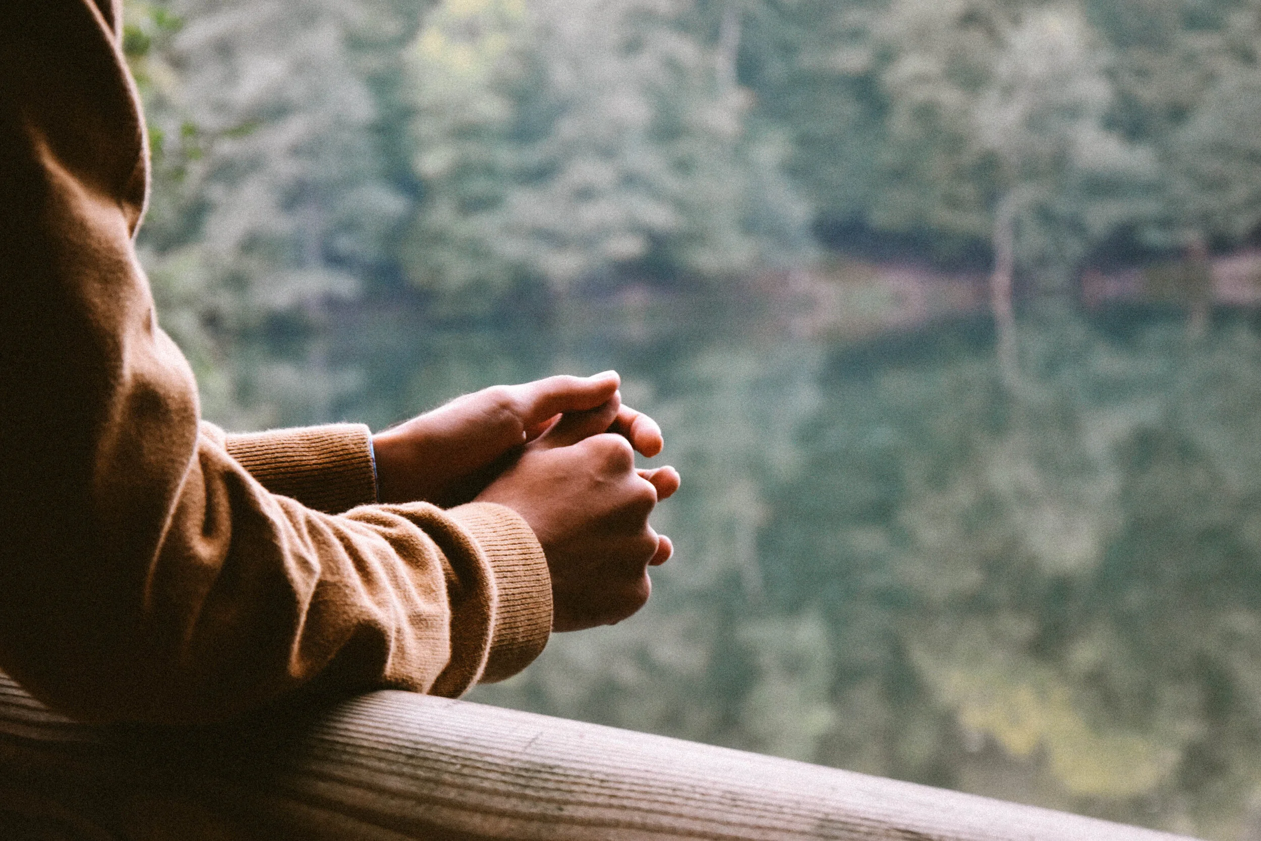 A person praying beside a window